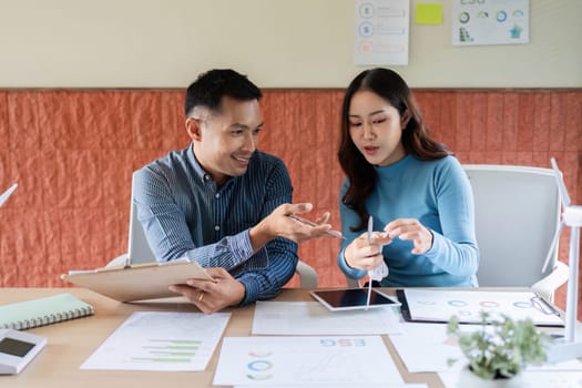 Colleagues engage in a productive conversation about ESG initiatives, evaluating documents and sharing insights.