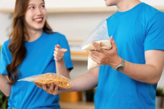 Two volunteers happily sharing food items, demonstrating teamwork and commitment to community welfare.