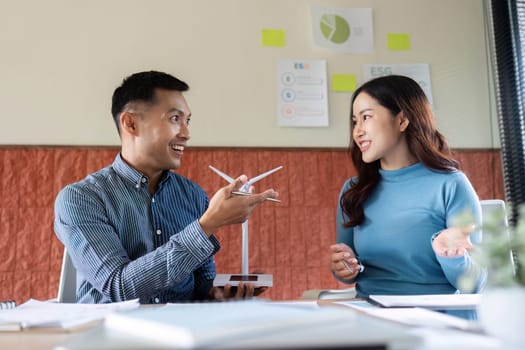 A man and a woman engage in a lively discussion about ESG strategies while showcasing a wind turbine model.