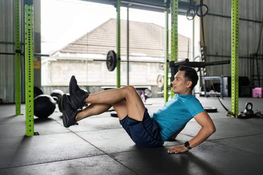 A male athlete executes a bicycle crunch, targeting abdominal muscles for strength and fitness in a gym setting.