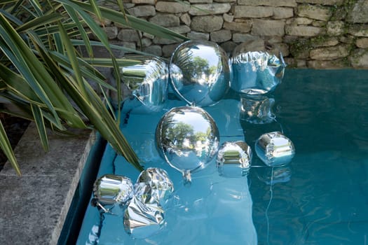 Silver balloons float in pools for a birthday party decorations