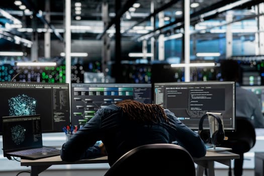 Exhausted server farm engineer falls asleep while using AI algorithms to analyze large datasets. Tired data center worker exhausted after using deep learning to recognize patterns in facility data