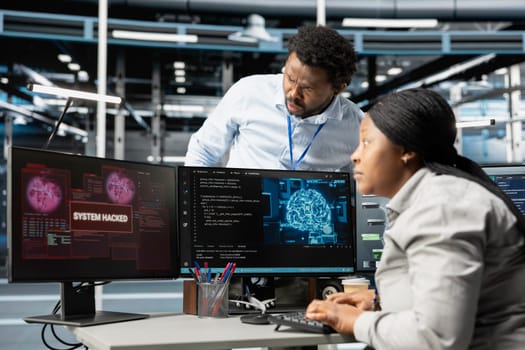 IT staff members in artificial intelligence server hub facility trying to protect servers from hackers. AI data center cybersecurity division colleagues protecting rigs during security breach
