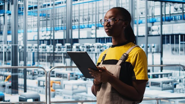 Smart factory engineer implements automated workflows and control systems using tablet, computerizing manual operations. Industry 4.0 worker integrates sensors into production using device, camera A