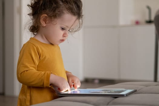 Child exploring creativity with a drawing app on a tablet in a modern living room environment.