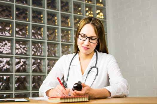A female doctor is fiiling a prescription