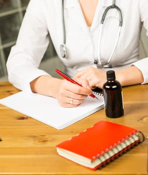 A female doctor is fiiling a prescription - close-up