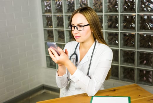 Hands of female medical worker using smartphone.