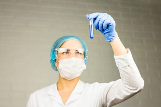 science, chemistry, biology, medicine and people concept - close up of young female scientist holding tube with sample making and test or research in clinical laboratory
