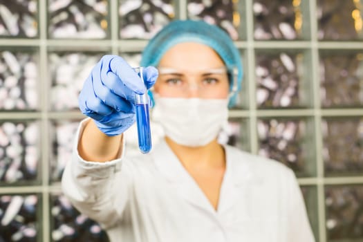 science, chemistry, biology, medicine, people concept - close-up of female scientist holding tube with sample making and test or research in clinical laboratory.