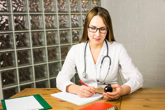 female doctor writing a prescription. young doctor writes a prescription drug in Notepad