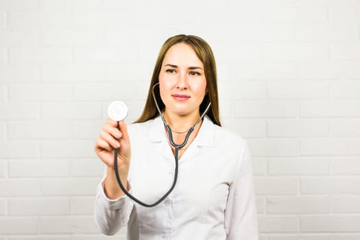 Female doctor with a stethoscope listening on white background