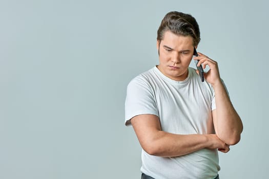 a man on a gray background is talking on the phone. High quality photo