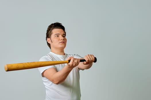 A man with a bat in his hands swings on a gray background. High quality photo