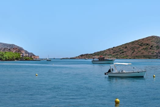 Romantic peaceful view of anchored fishermen's boats on a lagoon and against a hill on a sunny summer day. Crete island, Greece.