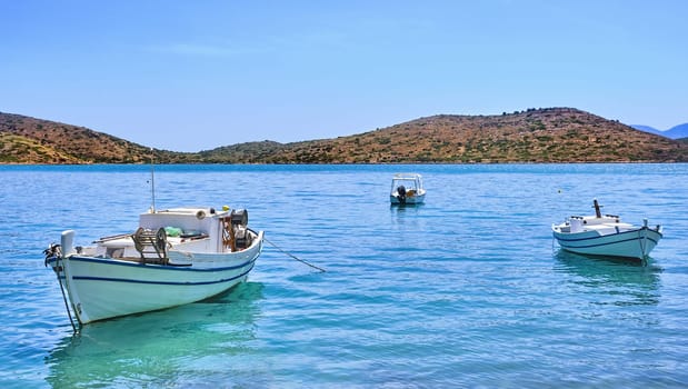 Romantic peaceful view of anchored fishermen's boats on a lagoon and against a hill on a sunny summer day. Crete island, Greece.