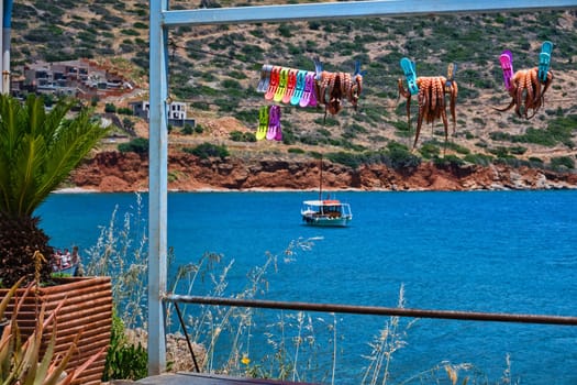 Traditional sun-dried octopuses clipped to rope with selective focus and typical Greek hills and fishermen's boat in background, calm sea, clear sunny summer day. Crete, Greece. selective focus