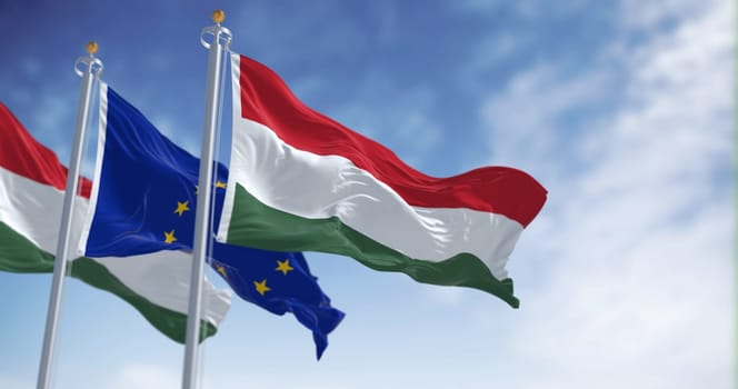 The flags of Hungary and the European Union fluttering together on a clear day. Hungary became a member of the European Union on 2004. 3d illustration render. Selective focus
