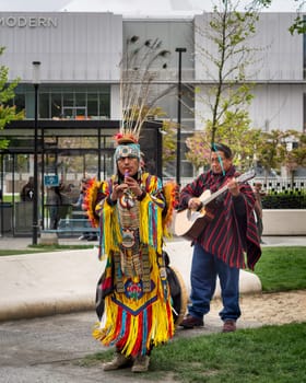 Istanbul, Turkey - May 5, 2023: Two Native Americans musicians wearing colorful traditional costume and busking playing courting flute and guitar in front of Istanbul Modern at Galataport, Karakoy