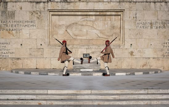 Ceremony of Presidential guard Evzones by the Greek tomb of Unknown Soldier. Evzones in summer uniform face each other, legs up. Close shot.