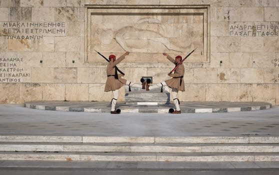 Ceremony of Presidential guard Evzones by the Greek tomb of Unknown Soldier. Evzones in summer uniform face each other, legs up, hands up. Close shot.
