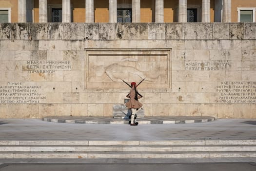 Ceremony of Presidential guard Evzones by the Greek tomb of Unknown Soldier. Evzones in summer uniform stand as one, knees up. Wide shot.