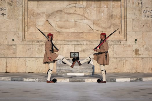 Ceremony of Presidential guard Evzones by the Greek tomb of Unknown Soldier. Evzones in summer uniform face each other, legs up. Close-up shot.