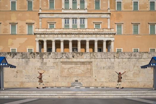 Ceremony of Presidential guard Evzones by the Greek tomb of Unknown Soldier. Evzones in summer uniform, march separately, hands up. Parliament building. Wide shot.