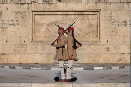Ceremony of Presidential guard Evzones by the Greek tomb of Unknown Soldier. Evzones in summer uniform stand as one, still. Medium shot.