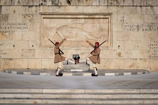 Ceremony of Presidential guard Evzones by the Greek tomb of Unknown Soldier. Evzones in summer uniform face each other, hands up, legs up. Close shot.
