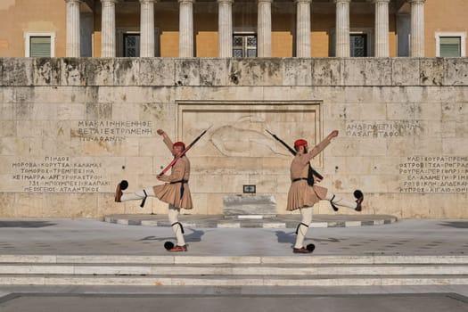 Ceremony of Presidential guard Evzones by the Greek tomb of Unknown Soldier. Evzones in summer uniform separate, hands up, legs up. Wide shot.