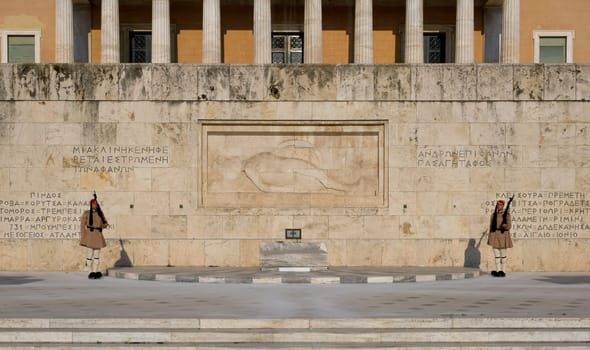 Evzones in summer uniform stand still on guard either side of the Tomb of Unknown soldier in afternoon. Wide shot.