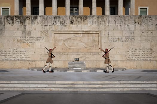 Ceremony of Presidential guard Evzones by the Greek tomb of Unknown Soldier. Evzones in summer uniform face each other, hands up. Wide shot.