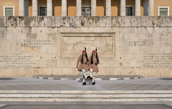Evzone stand in front of Tomb of Unknown Soldier, legs up, shoes touching. Wide shot