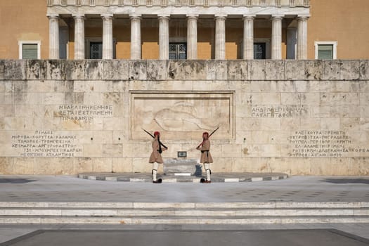 Ceremony of Presidential guard Evzones by the Greek tomb of Unknown Soldier. Evzones in summer uniform face each other, standing upright and still. Wide shot.