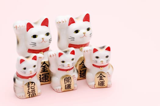 Japanese lucky cat on pink background, Japanese word of this photography means "better fortune, blessing, economic fortune"""
