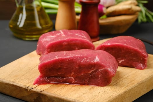 Closeup view of uncooked steaks on wooden cutting board
