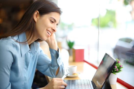 Happy woman in a coffee shop interior using digital tablet