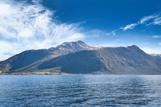 Fjord with mountains on horizon. Water glistens in the sun in Norway. Landscape photo from the north