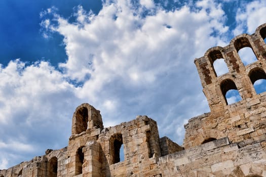 Diagonal dynamic composition of Odeon of Herodes Atticus theater arches on Acropolis hill, Athens, Greece, against bright blue sky and super clouds. Ancient ruins still used as venue for concerts, performances and festivals. UNESCO world heritage.