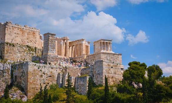 View of Acropolis hill from Areopagus hill in summer daylight with great clouds in blue sky, Athens, Greece. UNESCO world heritage. Propylaea entrance, Agrippa's monument, Parthenon. Fresh green foliage. Close shot