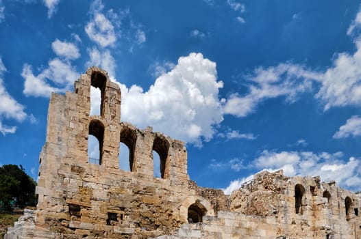 Diagonal dynamic composition of Odeon of Herodes Atticus theater arches on Acropolis hill, Athens, Greece, against bright blue sky and super clouds. Ancient ruins still used as venue for concerts, performances and festivals. UNESCO world heritage.