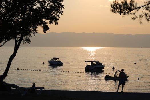 Evening mood on the Adriatic coast off Omisalj/island Krk in Croatia - boats lying near the beach in the water,a man enjoys the atmosphere  Theme picture Croatia / Hrvatska / Croatia 2023