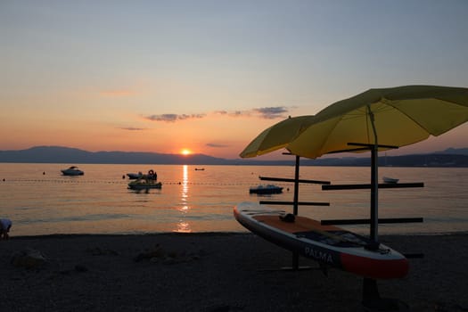 Evening mood on the Adriatic coast off Omisalj/island Krk in Croatia,boats are in the water,a SUP stands with umbrellas on the shore   Theme picture Croatia / Hrvatska / Croatia 2023