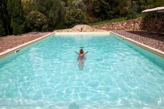 Woman swimming in pool during vacation in Montemassi. Italy