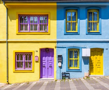 Exterior facade of colorful twin houses with walls painted in vivid colors, wooden doors, and wrought iron windows, at a narrow alley, Uskudar district, Istanbul, Turkey