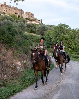 Montemassi, Italy - September 13, 2022: A woman and two girls during a horseback ride on a gravel road in Montemassi, Italy
