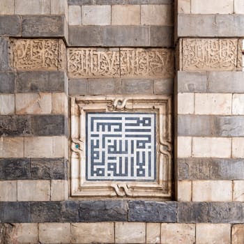 Marble decoration unit with Islamic calligraphy on the exterior stone wall of Sultan al Muayyad Mosque, Old Cairo, Egypt. Text translates: In The Name of Allah, the Beneficent, the Merciful