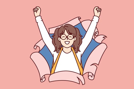 Overjoyed little girl from elementary school with smile raises hands up, looking out of torn paper. Cheerful schoolgirl celebrating victory in olympiad or good mark for lesson by school teacher