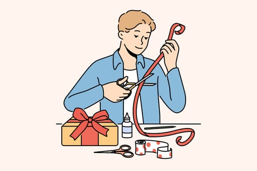 Man makes gift with own hands decorating box with red ribbon with festive paper. Romantic guy prepares beautiful DIY gift for valentine day and birthday and christmas for beloved girlfriend